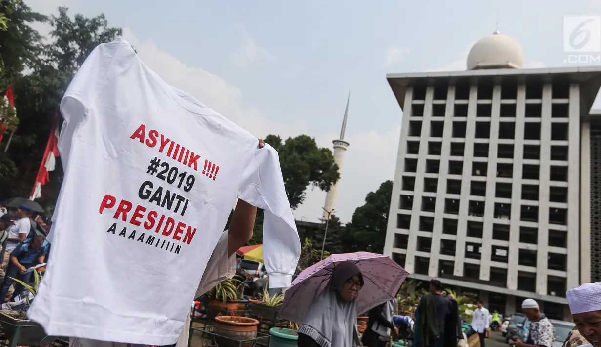 Pedagang menjual kaos #2019GantiPresiden di halaman Masjid Istiqlal, Jakarta, Jumat (10/8). Mereka memanfaatkan peluang berdagang usai deklarasi Capres dan Cawapres. (Liputan6.com/Fery Pradolo)