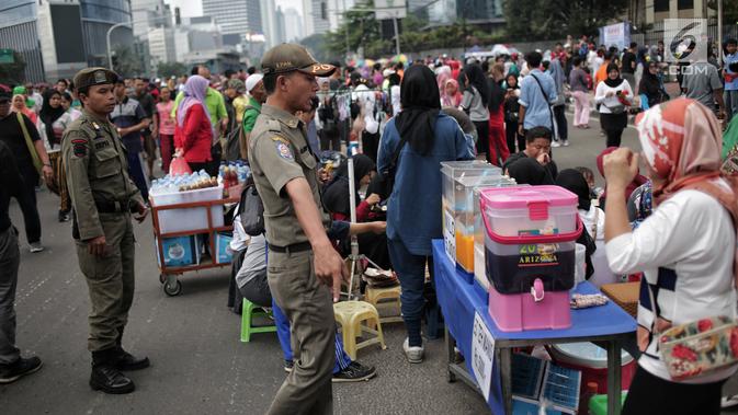 Satpol PP DKI Jakarta menertibkan PKL yang berdagang di kawasan Car Free Day, Bundaran HI, Jakarta, Minggu (20/1). Penertiban dilakukan karena telah membuat ketidaknyamanan bagi para pengunjung CFD yang ingin berolahraga. (Liputan6.com/Faizal Fanani)