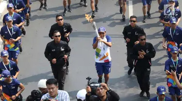 Pelari membawa obor Asian Games 2018 dalam Torch Relay Asian Games 2018 di kawasan TMII, Jakarta Timur, Rabu (15/8). Kota Jakarta menjadi persinggahan terakhir api Asian Games yang dimulai dari wilayah Jaktim dan Jaksel. (Liputan6.com/Immanuel Antonius)