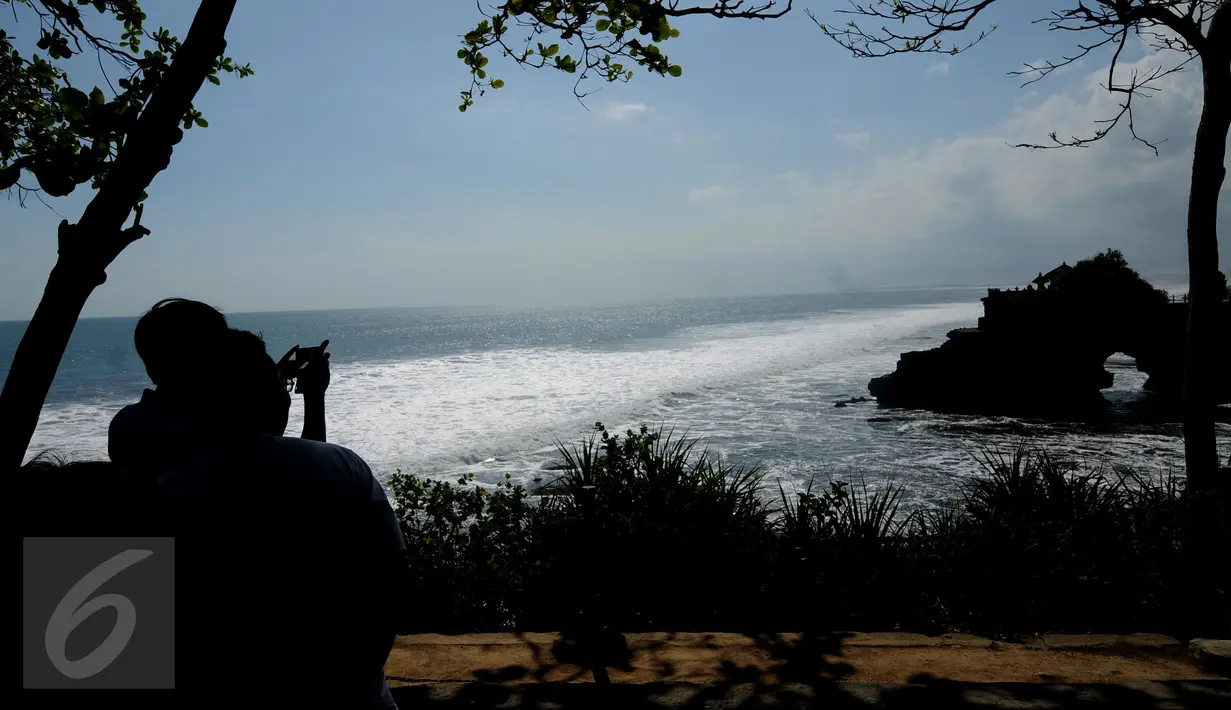 Wisatawan mengabadikan bangunan pura yang berdiri di atas karang bolong di kawasan wisata Tanah Lot, Bali, 31 Agustus 2015. Kawasan wisata Tanah Lot masih menjadi primadona bagi wisatawan yang berkunjung ke Bali. (Liputan6.com/Helmi Fithriansyah)