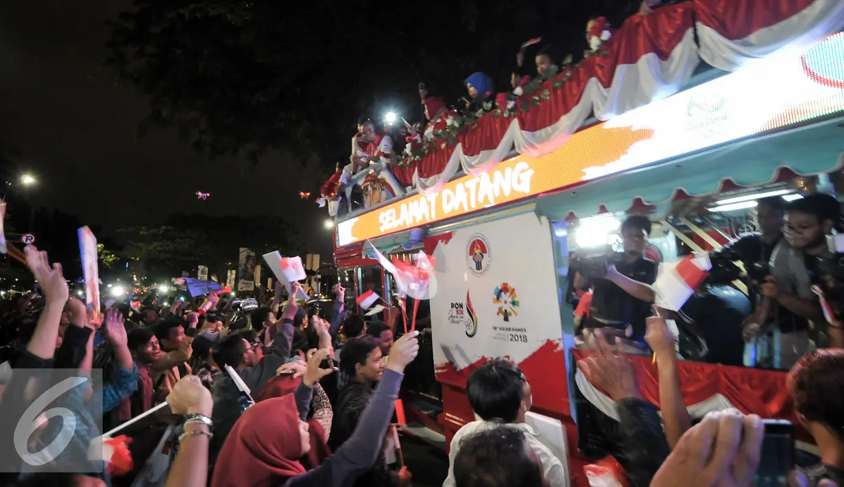 Warga menyambut arak-arakan atlet Indonesia yang berjuang di Olimpiade Rio 2016, Jakarta, Selasa (23/8). Setibanya di Tanah Air, atlet Olimpiade diarak menggunakan bus Bamdros menuju gedung Kementerian Pemuda dan Olahraga. (Liputan6.com/Yoppy Renato)