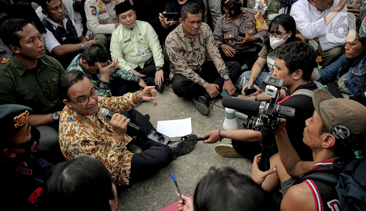 Gubernur DKI Jakarta Anies Baswedan berdiskusi dengan pendemo yang tengah melakukan orasi di depan gerbang Balai Kota DKI Jakarta, Jumat (14/10/2022). Anies melakukan diskusi dengan salah seorang perwakilan demonstran sembari disaksikan peserta unjuk rasa lain. (Liputan6.com/Faizal Fanani)
