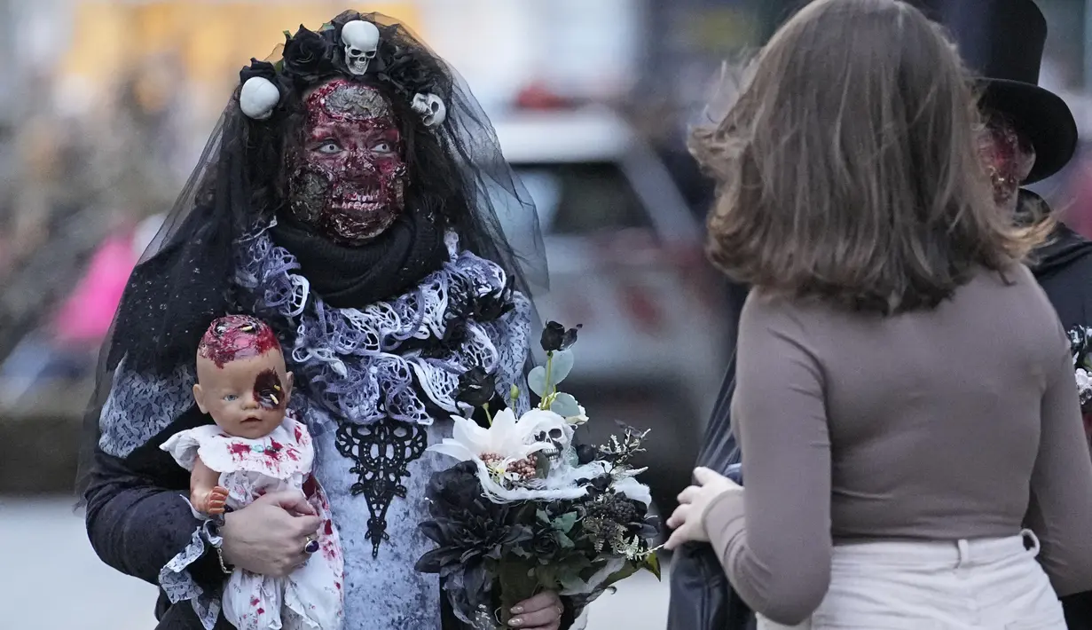 Orang-orang yang mengenakan kostum menakutkan tiba di pusat kota untuk Zombie Walk dan Parade Halloween tahunan di Essen, Jerman, Minggu (31/10/2021). Setiap 31 Oktober sebagian masyarakat dunia ikut memeriahkan perayaan Halloween. (AP Photo/Martin Meissner)
