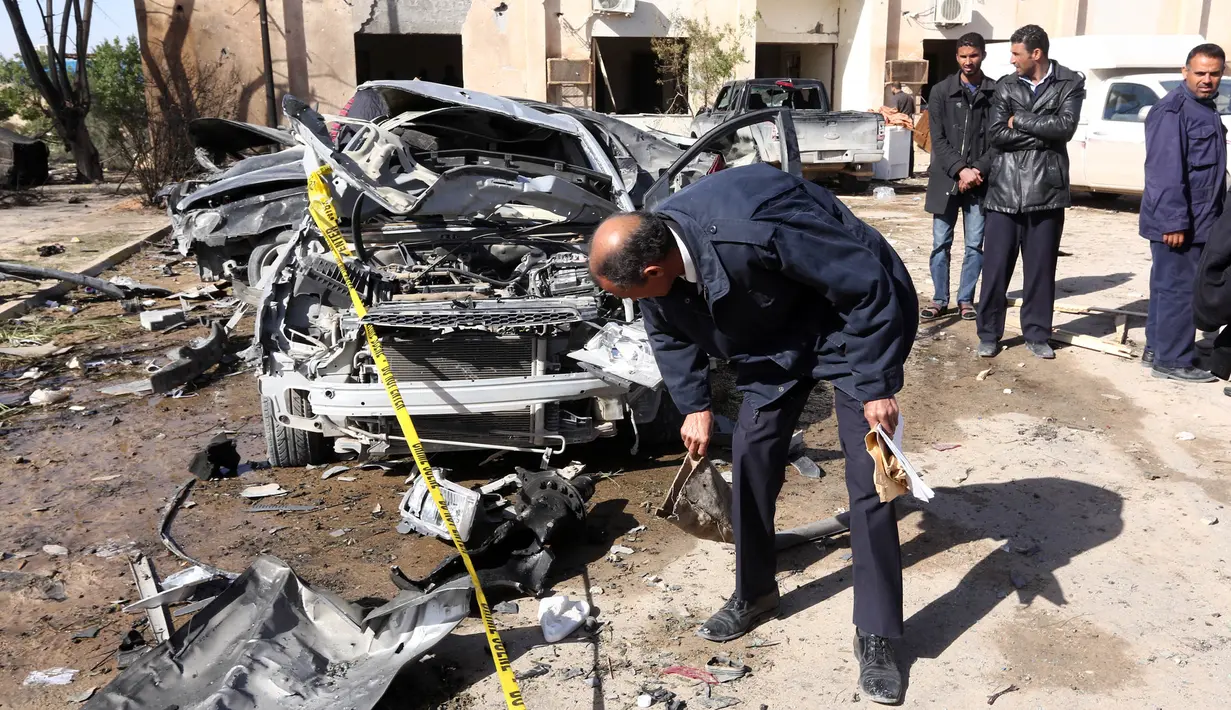 Petugas memeriksa sebuah mobil yang rusak akibat bom truk yang meledak di sekolah polisi di kota Zliten, wilayah barat Libya, Kamis (7/1). Belum ada yang mengaku bertanggung jawab terkait serangan bom yang menewaskan 50 orang itu (AFP PHOTO/MAHMUD Turkia)