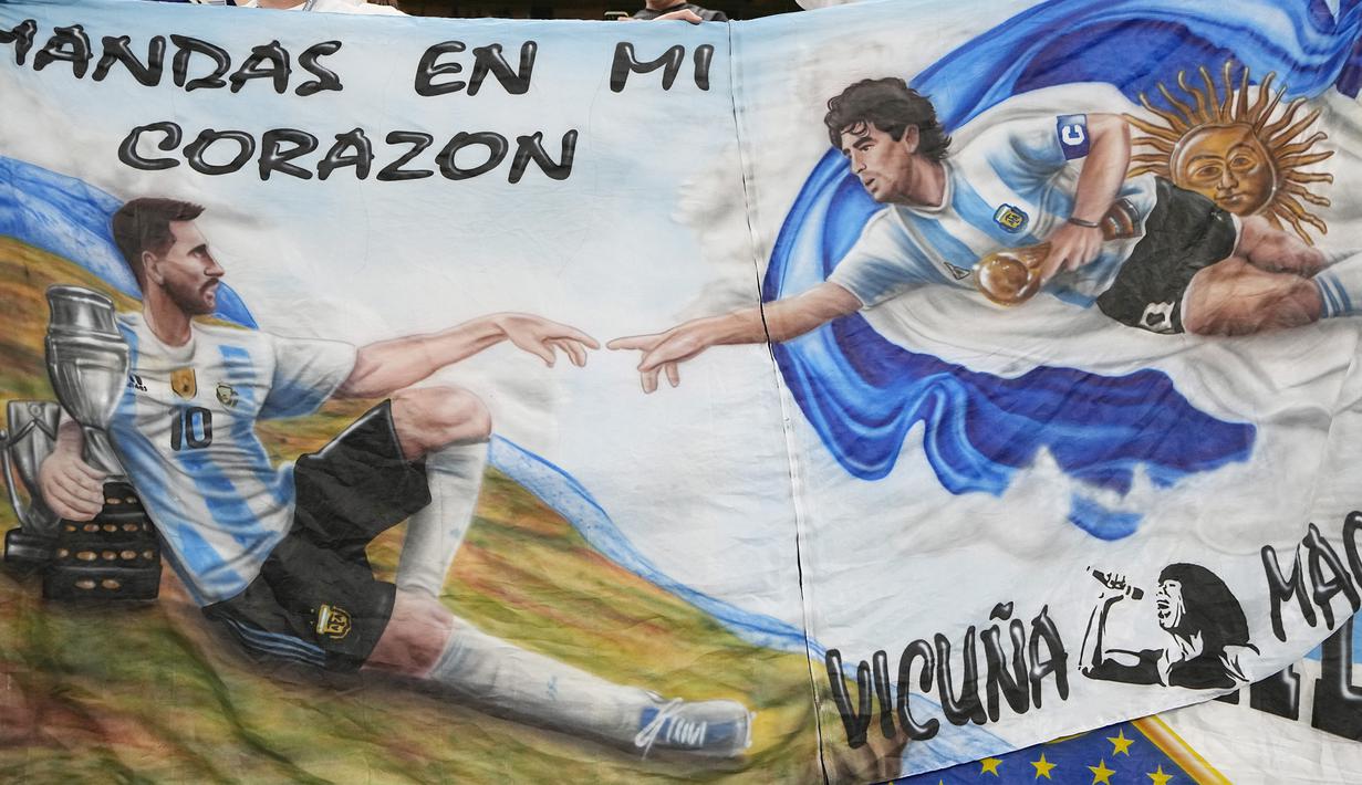 Lukisan bergambar Lionel Messi dan Diego Maradona dibawa oleh suporter saat menyaksikan laga antara Argentina melawan Meksiko. Lionel Messi kini bisa berbangga hati usai gol yang dicetak ke gawang Meksiko membuat dirinya sejajar dengan Diego Maradona. (AP Photo/Ariel Schalit)