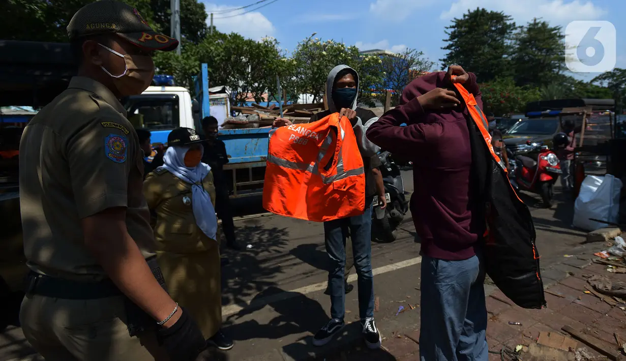 Warga mengenakan rompi pelanggar PSBB (Pembatasan Sosial Berskala Besar) saat terjaring razia di Pasar Gembrong, Jakarta, Selasa (2/6/2020). Para pelanggar aturan PSBB tersebut dijatuhi sanksi membayar denda atau melakukan pelayanan sosial. (merdeka.com/Imam Buhori)