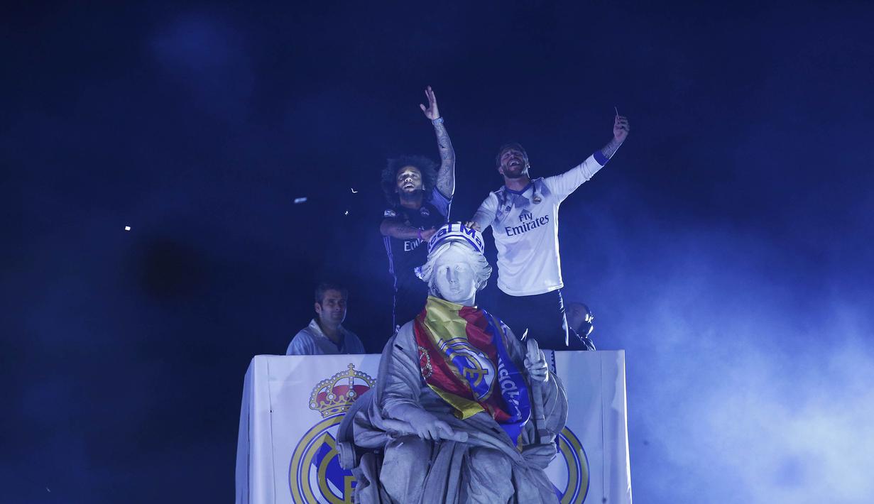 Pemain Real Madrid, Sergio Ramos dan Marcelo memberi salam kepada suporter di monumen Cibeles saat merayakan keberhasilan mereka menjuarai La Liga Spanyoll (22/05/2017). Real Madrid meraih juara La Liga untuk ke-33 kalinya. (AP/Francisco Seco)