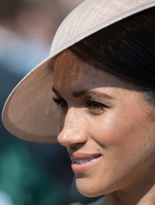 Duchess of Sussex, Meghan Markle menghadiri pesta kebun Istana Buckingham di London, Selasa (22/5). Lipstik nude beige tampak menghiasi bibir Meghan dengan paduan riasan mata yang simpel. (Dominic Lipinski/Pool Photo via AP)