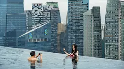 Sepasang suami istri mengambil foto mereka dari kolam renang atap dari Marina Bay Sands resort hotel yang menghadap cakrawala kota di Singapura, Selasa (20/05/2014) (AFP PHOTO/Roslan Rahman)