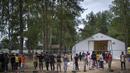 Para migran berdiri di pagar di kamp pengungsi yang baru dibangun di tempat latihan militer Rudninkai, Lithuania, Rabu (4/8/2021). Sekitar 4.090 migran, kebanyakan dari Irak, telah menyeberang tahun ini dari Belarus ke Lithuania. (AP Photo/Mindaugas Kulbis)