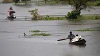 Penduduk desa mendayung perahu-perahu desa dengan barang bawaan mereka untuk pindah ke daerah-daerah yang lebih aman melalui banjir di distrik Morigaon di Assam, India (26/6/2020). (AP Photo/Anupam Nath)