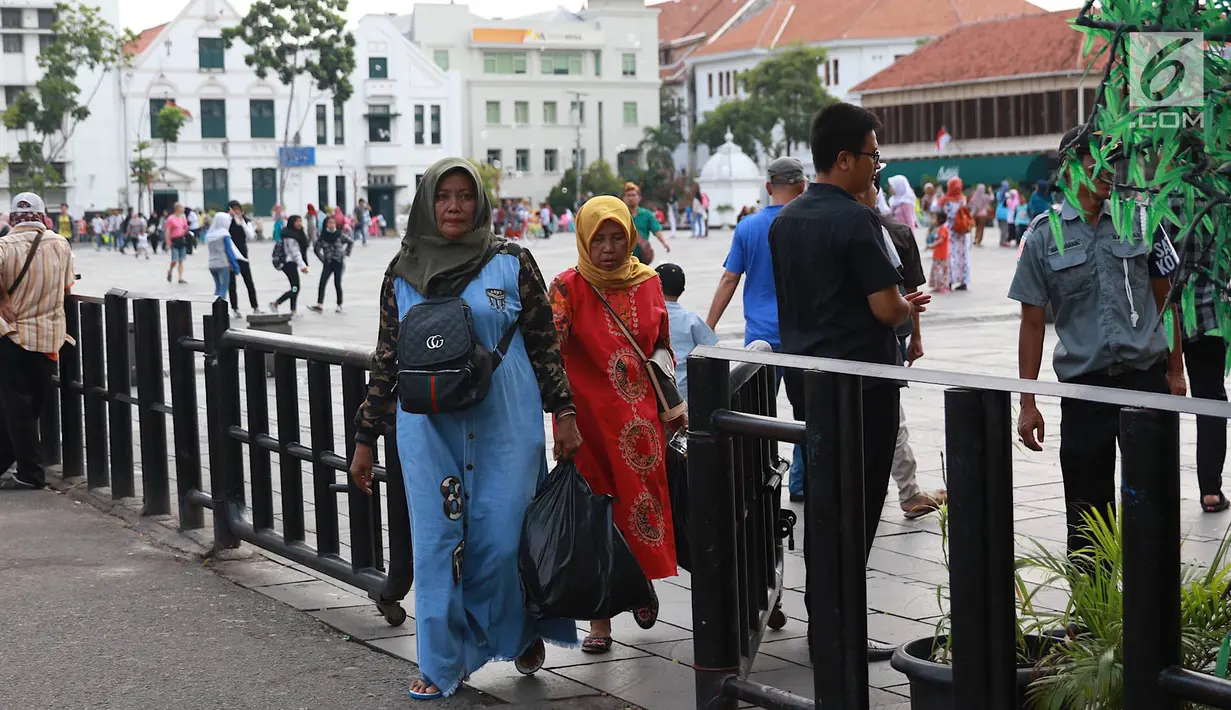 Pejalan kaki melintasi jalur masuk dan keluar Taman Fatahilah saat uji coba simulasi di kawasan Kota Tua, Jakarta, Selasa (23/4). Penataan akses tersebut dilakukan untuk memperlancar keluar masuknya pengunjung ke kawasan wisata tersebut. (Liputan6.com/Immanuel Antonius)