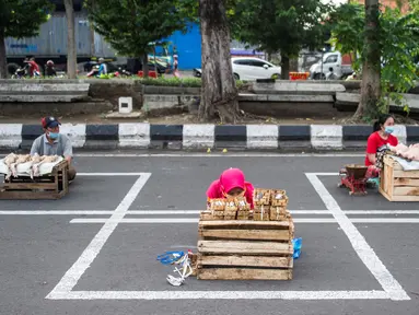 Pedagang menjual dagangannya di antara petak-petak untuk menerapkan jaga jarak (physical distancing) di sepanjang jalan di Surabaya, Selasa (2/6/2020). Garis petak-petak bagi pedagang itu sebagai langkah pencegahan penyebaran COVID-19. (Photo by Juni Kriswanto / AFP)