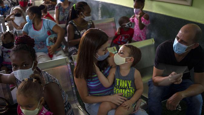 Orang tua menemani anak mereka yang akan menerima vaksin COVID-19 Soberana-02 di sebuah klinik di Havana, Kuba, Kamis (17/9/2021) (AP Photo/Ramon Espinosa)