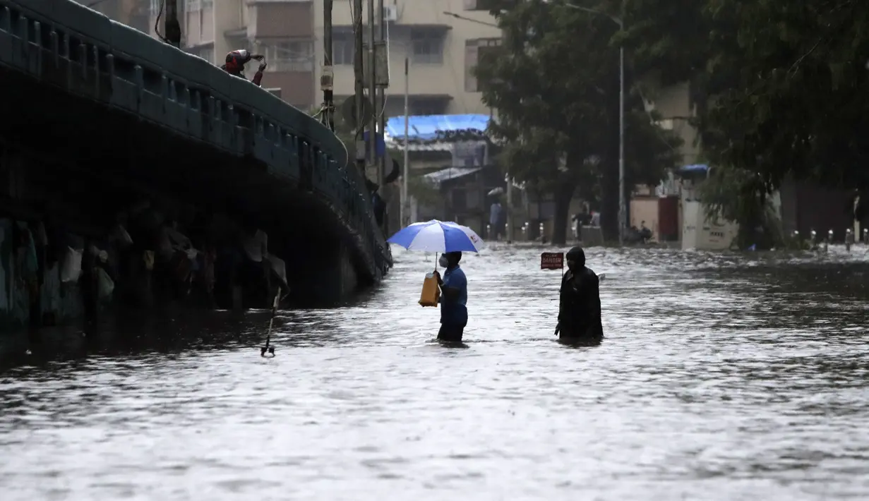 Orang-orang menyeberang jalan melintasi banjir saat hujan lebat di Mumbai, India, Rabu, (5/8/2020). Musim hujan India berlangsung dari Juni hingga September. (AP Photo/Rajanish Kakade)