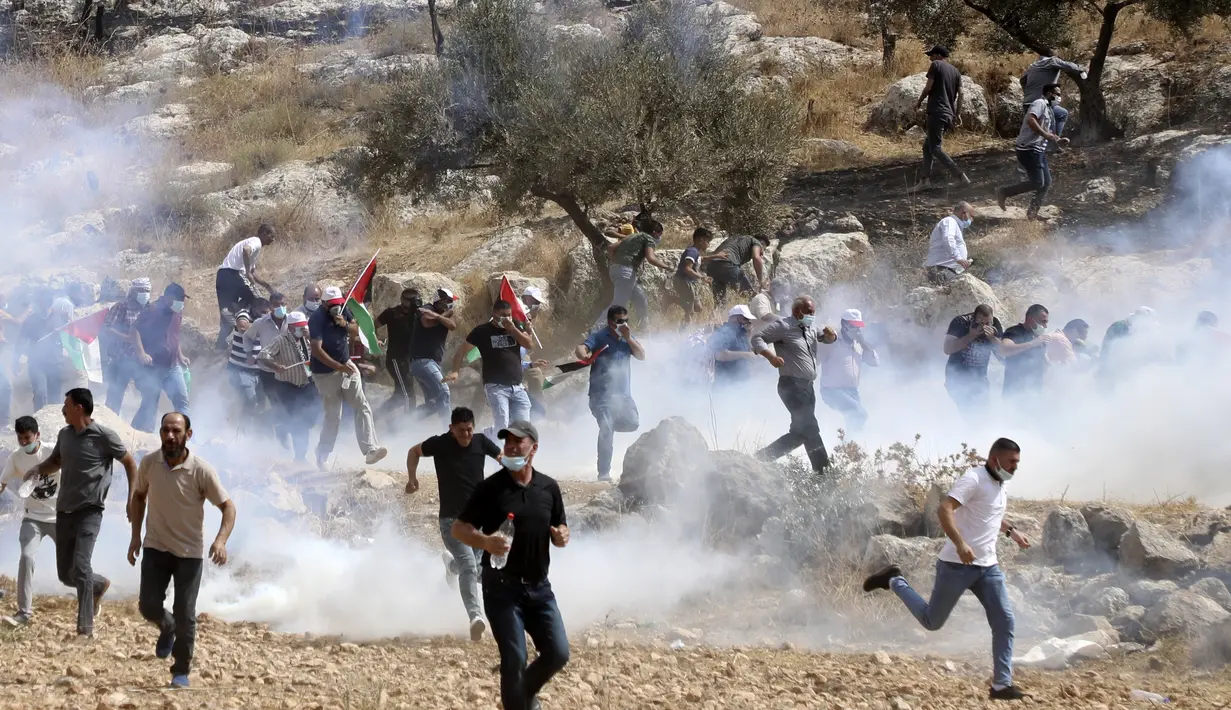 Pengunjuk rasa Palestina menghindari gas air mata yang ditembakkan tentara Israel saat memprotes pencaplokan tanah untuk perluasan permukiman Yahudi di dekat desa Beit Dajan, timur Nablus, Palestina (9/10/2020). (AFP/Jaafar Ashtiyeh)