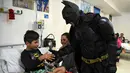 Seorang pria berkostum Batman menyalami seorang pasien anak di RS Anak 'Sor Maria Ludovica' di La Plata, Buenos Aires, Argentina, Jumat (2/6). Kehadiran Batman ini menjadi hiburan bagi anak-anak di rumah sakit tersebut. (AFP FOTO / Eitan ABRAMOVICH)