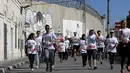 Sejumlah peserta berlari menyusuri tembok pemisah Israel selama Right to Movement Maraton di kota Bethlehem, Palestina, Jumat (1/4). Tembok sejauh 700 km ini dijadikan obyek berlari para peserta. (REUTERS / Ammar Awad)