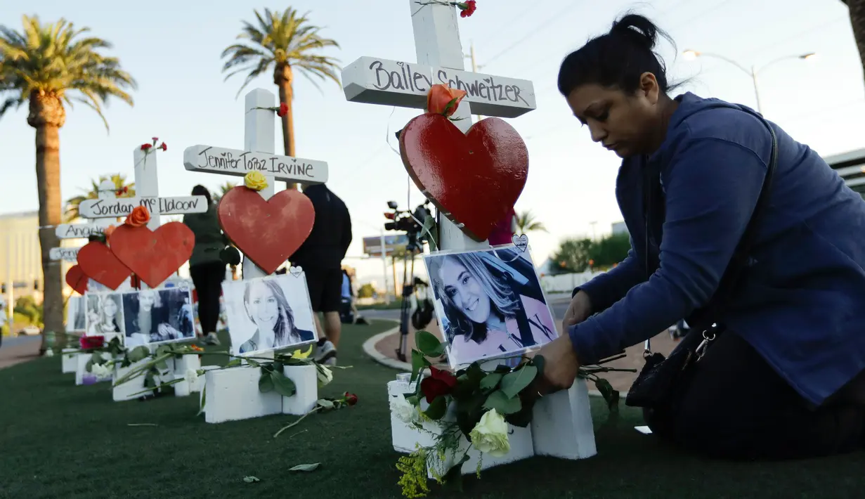 Cece Navarrette meletakkan bunga di sebuah nisan milik saudaranya, Bailey Schweitzer yang menjadi korban penembakan massal di Las Vegas, Jumat (6/10). Sebanyak 58 nisan kayu berbentuk salib itu ditambahkan ornamen hati berwarna merah. (AP/Gregory Bull)