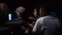 Warga Bandung dengan segala cara menggunakan gadget untuk menonton laga Persib saat terjadi pemadaman listrik, Senin (4/9/2017) malam. (Bola.com/Muhammad Ginanjar)