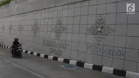 Pengendara motor melewati coretan di dinding underpass atau lintas bawah Matraman, Jakarta Selatan, Rabu (2/5). Corat-coret tersebut terpampang jelas ketika melintas dari arah Jalan Tambak menuju kawasan Pramuka. (Liputan6.com/Arya Manggala)