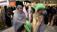 Ilustrasi perempuan dengan sekarung tepung terigu gratis di tempat distribusi sembako Ramadhan di Lahore, Pakistan [File: KM Chaudary/AP]