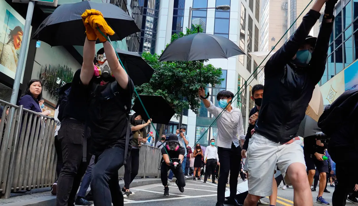 Demonstran mencoba menembakkan barang menggunakan sling shot saat demonstrasi di Hong Kong, Senin (11/11/2019). Ketegangan di Hong Kong semakin meningkat setelah polisi menembak seorang demonstran hingga kritis. (AP Photo/Vincent Yu)