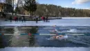 Para perenang bertanding saat kompetisi renang musim dingin di lubang es sepanjang 25 meter di sebuah danau dekat Vilnius, Lithuania, Sabtu (6/3/2021).  Suhu air saat itu 3 derajat Celcius, sedangkan udaranya -3 derajat Celsius. (AP Photo/Mindaugas Kulbis)