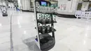 Sebuah gambar pada 15 Juni 2021 menunjukkan robot pembawa air Zamzam yang digunakan pertama kalinya di sekitar Masjidil Haram di Makkah, Arab Saudi. Robot itu masing-masing dilengkapi tiga rak berisi air zamzam botolan sehingga para jemaah bisa mengambil sendiri tanpa kontak langsung. (AFP Photo)