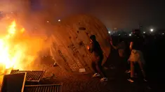Demonstran menggulung gulungan kabel kayu ke barikade yang terbakar saat protes RUU Pensiun di Paris, Prancis, Jumat (17/3/2023). (AP Photo/Lewis Joly)