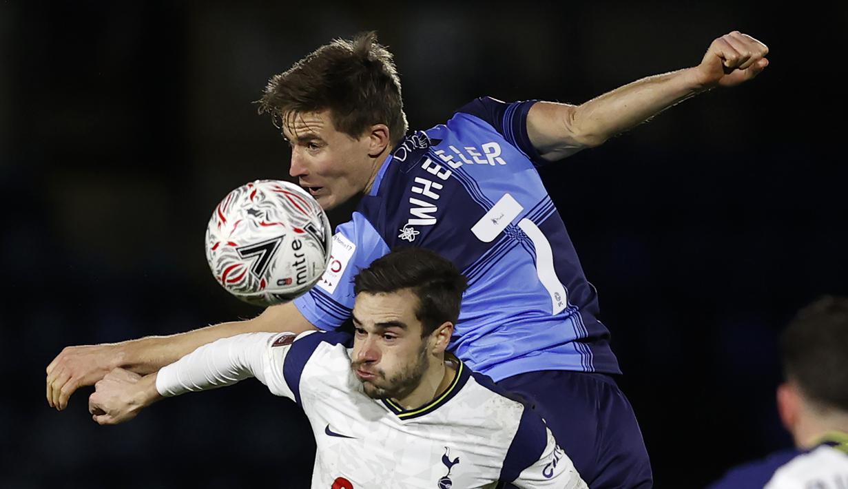 Gelandang Wycombe Wanderers, David Wheeler (atas) berduel udara dengan gelandang Tottenham Hotspur, Harry Winks dalam laga babak keempat Piala FA 2020/21 di Adams Park Stadium, Senin (25/1/2021). Wycombe Wanderers kalah 1-4 dari Tottenham Hotspur. (AFP/Adrian Dennis)