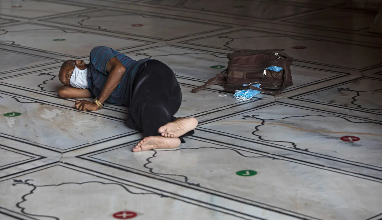 Seorang penjual masker beristirahat di lantai Masjid Jama yang dibuka kembali setelah pemerintah melonggarkan lockdown di kawasan Kota Tua Delhi, Selasa (7/7/2020). India pada 6 Juli menjadi negara dengan jumlah virus corona tertinggi ketiga di dunia. (Photo by XAVIER GALIANA / AFP)