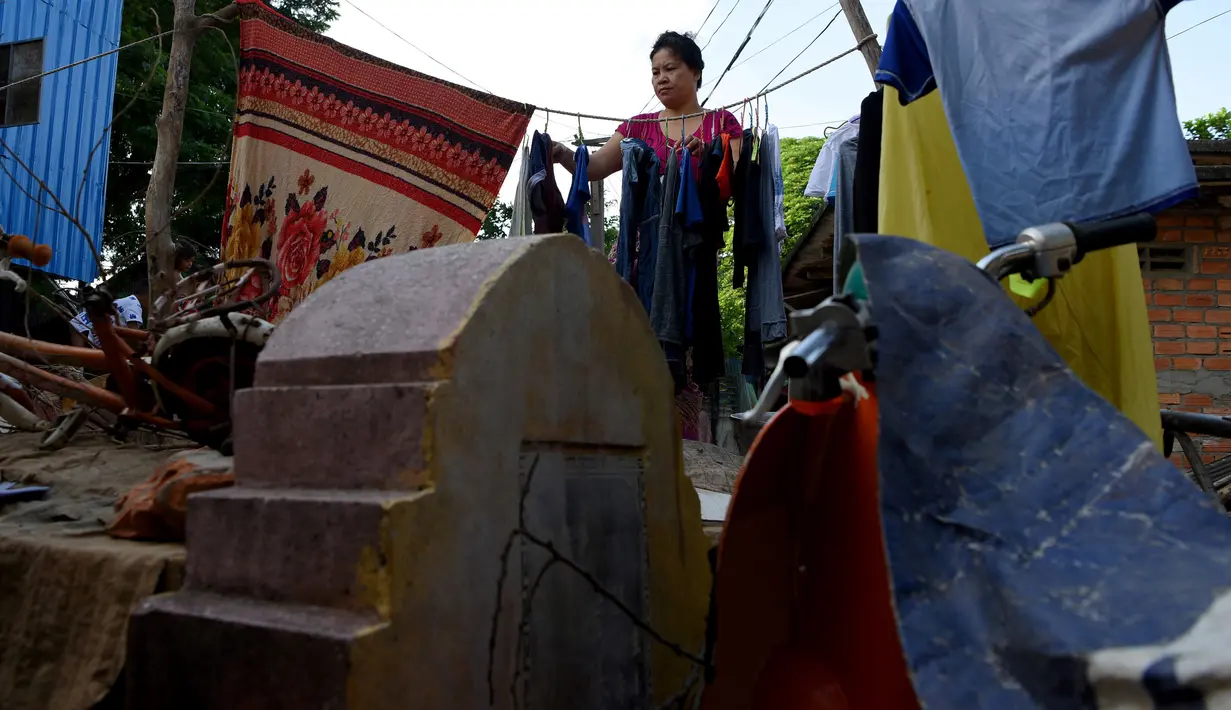 Seorang wanita menjemur pakaian di area kuburan di Phnom Penh, Kamboja pada 5 Juni 2019. Pemakaman menjadi tempat peristirahatan abadi bagi orang mati, tetapi area pemakaman ini menjelma sebagai tempat tinggal untuk bertahan hidup bagi mereka yang didera kemiskinan. (TANG CHHIN Sothy/AFP)
