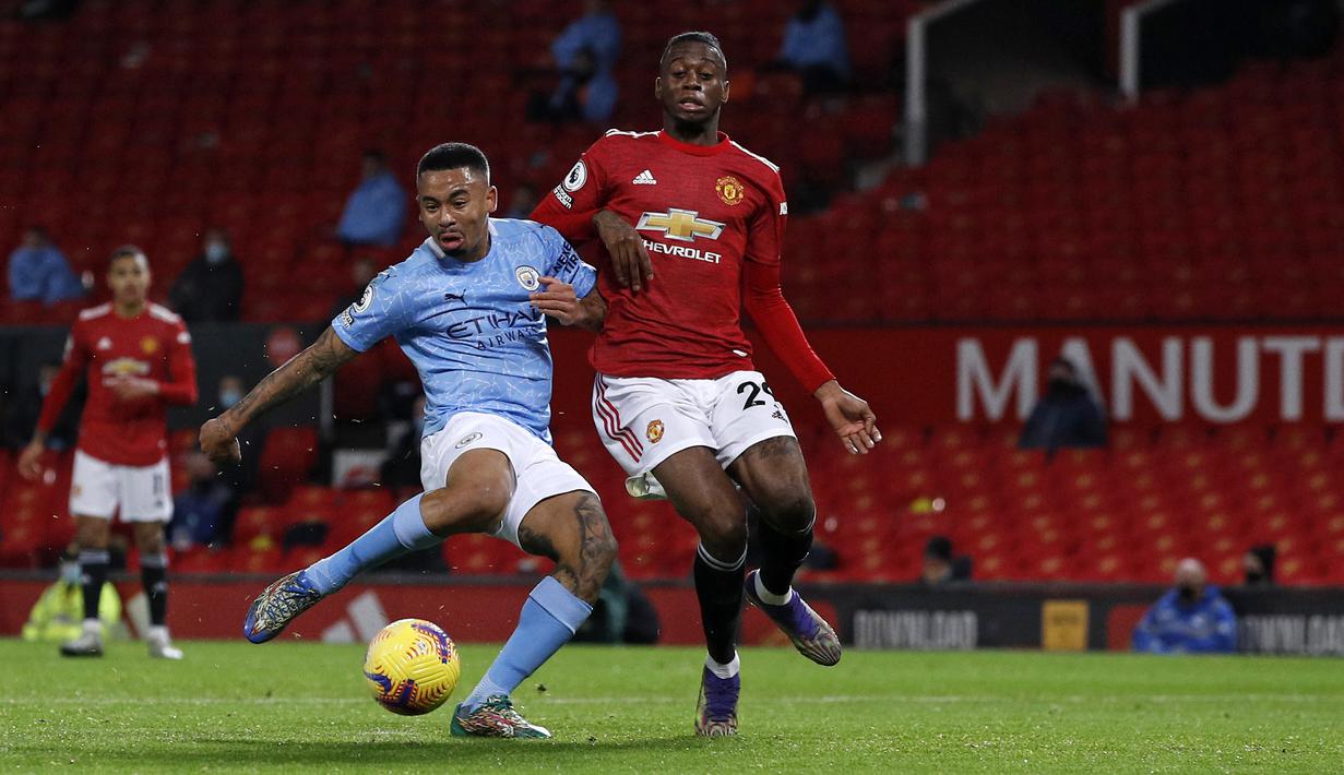 Striker Manchester City, Gabriel Jesus (kiri), berebut bola dengan bek Manchester United, Aaron Wan-Bissaka dalam laga lanjutan Liga Inggris 2020/21 pekan ke-12 di Old Trafford Stadium, Sabtu (12/12/2020). Manchester City bermain imbang 0-0 dengan Manchester United. (AFP/Phil Noble/Pool)