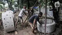 Pekerja menyelesaikan pembangunan sumur resapan di RPTRA Meruya Utara, Jakarta, Selasa (25/1/2022). Pembangunan 100 titik sumur resapan ini bertujuan untuk mengantisipasi banjir yang kerap terjadi di wilayah tersebut. (merdeka.com/Iqbal S. Nugroho)