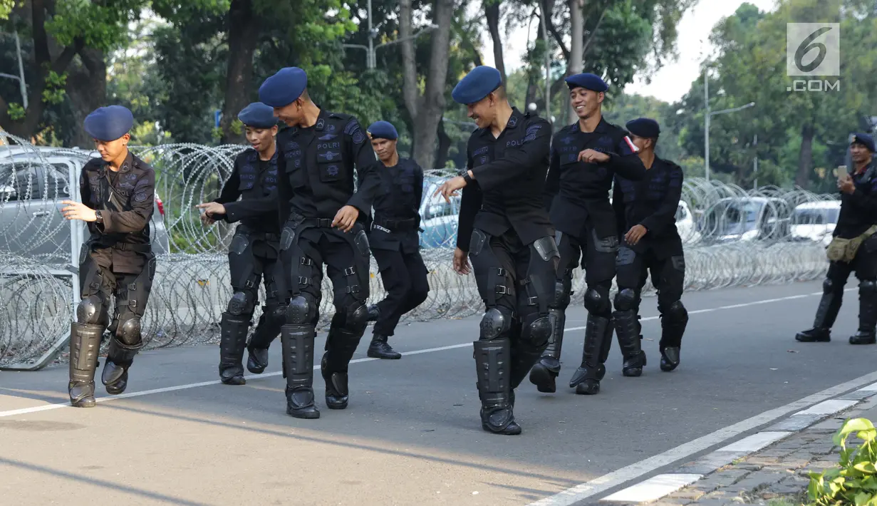 Personel Brimob menari bersama disela-sela berjaga di depan Gedung Mahkamah Konstitusi (MK), Jakarta, Selasa (25/6/2019). Jelang sidang pembacaan putusan akan digelar pada Kamis (27/6), penjagaan di sekitar Gedung Mahkamah Konstitusi diperketat. (Liputan6.com/Helmi Fithriansyah)