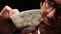 Pegawai rumah lelang Sotheby's memeng mangkuk falangcai dari Dinasti Qing selama pratinjau media di Hong Kong, Kamis (30/8). Mangkuk akan dilelang pada 3 Oktober 2018. (AP Photo/Kin Cheung)