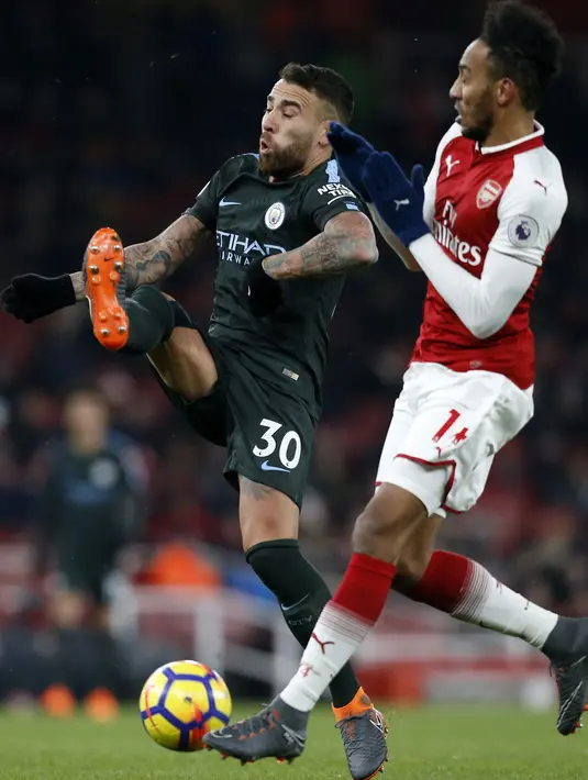 Bek Manchester City, Nicolas Otamendi berebut bola dengan striker Arsenal, Pierre-Emerick Aubameyang pada laga pekan ke-28 Premier League di Emirates Stadium,  Jumat (2/3). Manchester City menang telak tiga gol tanpa balas atas Arsenal. (Glyn KIRK/AFP)