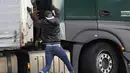 Migran melompati truk untuk mencoba menyeberangi terowongan menuju Inggris di Calais, Prancis pada 14 Oktober 2021. Dalam praktik berbahaya dan berpotensi mematikan, ia mencoba melewati terowongan yang dijaga ketat yang menghubungkan kedua negara dengan bersembunyi di truk. (AP/Christophe Ena)