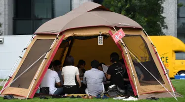 Foto 11 September 2018, karyawan perusahaan bekerja di dalam tenda kemah di halaman luar gedung kantor di Tokyo. Beberapa kantor di Jepang membebaskan pegawainya untuk bekerja di mana saja, mulai dari tenda hingga tempat karaoke. (Toshifumi KITAMURA/AFP)