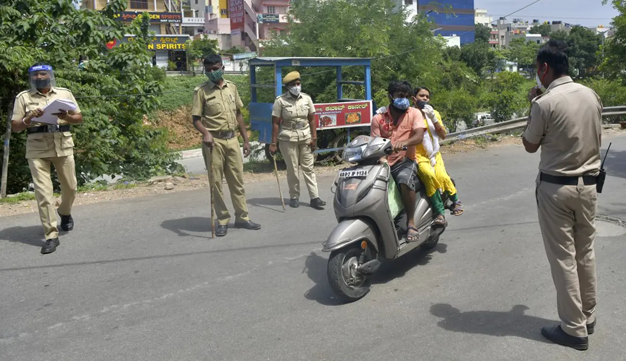 Polisi menghentikan pengendara untuk memeriksa dokumen identifikasi mereka selama penguncian yang diberlakukan sebagai tindakan pencegahan terhadap penyebaran COVID-19 di Bangalore, India, Senin (24/5/2021). Kematian akibat COVID-19 di India telah menembus 300 ribu orang. (Manjunath Kiran/AFP)