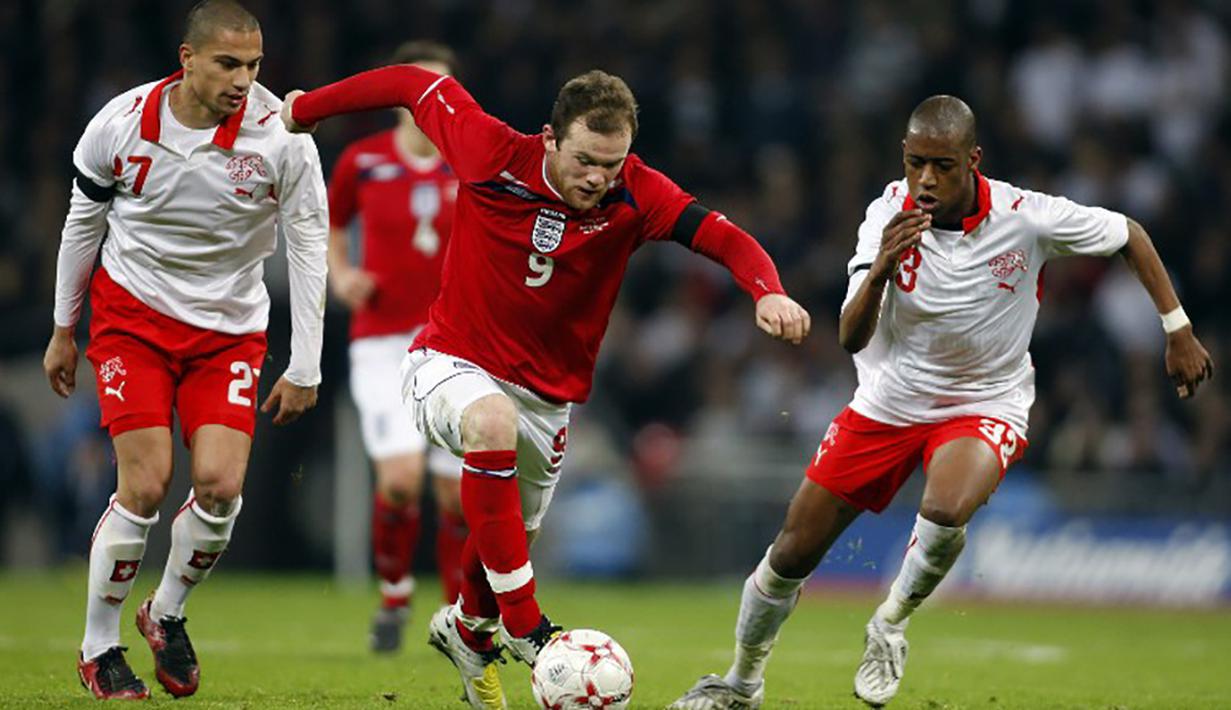 Wayne Rooney berusaha melewati hadangan pemain Swiss, Gelson Fernandes pada laga persahabatan di Stadion Wembley, Inggris, Rabu (6/2/2015). (AFP Photo/Adrian Dennis) 