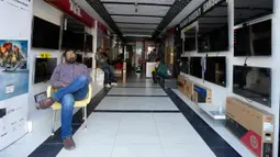 Seorang penjaga toko dan pekerja menunggu listrik menyala menyusul pemadaman listrik nasional di toko elektronik di Karachi, Pakistan, Senin (23/1/2023). Pemadaman listrik terjadi karena terdapat kerusakan besar pada jaringan listrik nasional. (AP Photo/Fareed Khan)