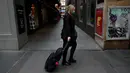 Seorang perempuan menarik tas di sepanjang trotoar di daerah pusat kota Melbourne yang tenang ketika pihak berwenang mengumumkan lockdown (penguncian) untuk keenam kalinya di kota itu dalam upaya untuk menghentikan penyebaran Covid-19 varian delta, pada Kamis (5/8/2021). (Con Chronis/AFP)