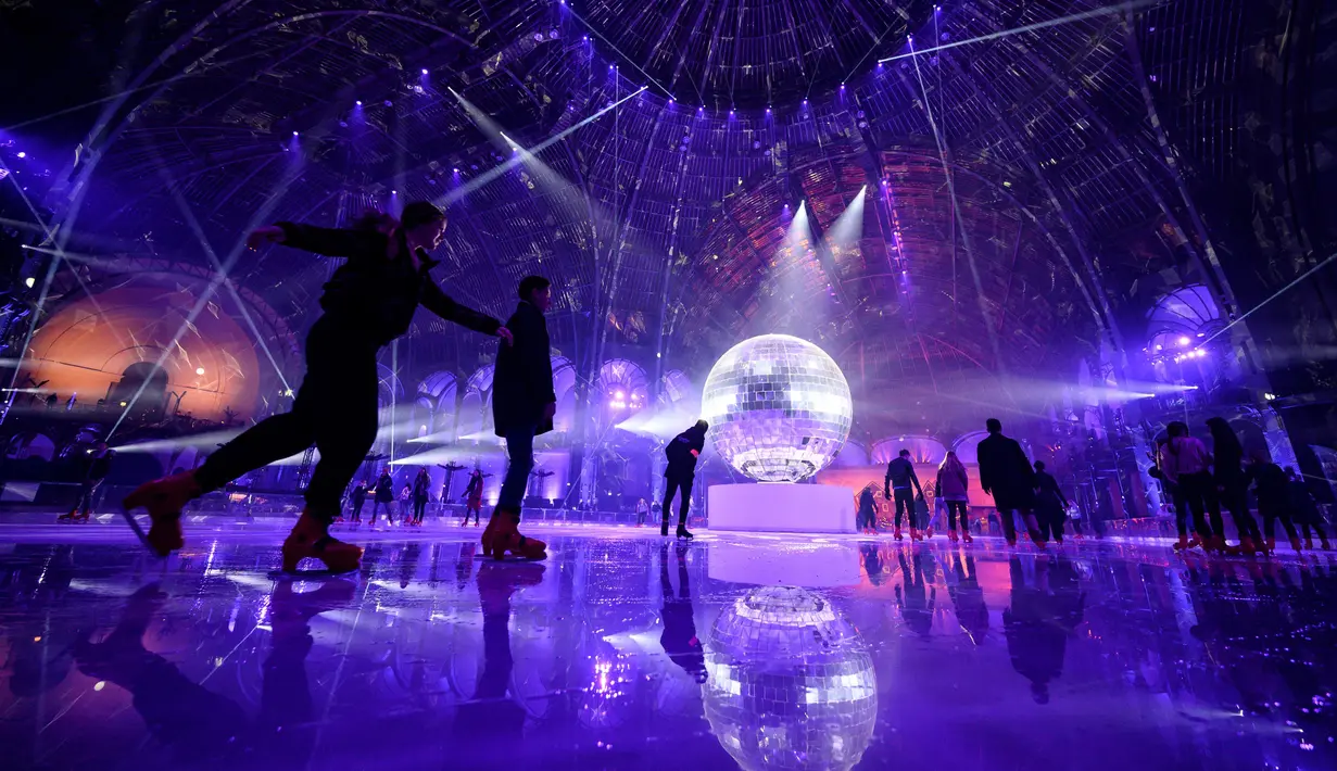 Orang-orang berseluncur di arena ice skating di bawah kubah kaca mewah legendaris, Grand Palais, Paris, Selasa (17/12/2019). Aren seluncur es musiman ini terbuka untuk umum selama liburan Natal. (Photo by Thomas SAMSON / AFP)