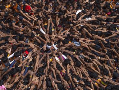 Orang-orang memberikan penghormatan sebelum membentuk piramida manusia untuk mencapai pot tanah yang menjorok  saat merayakan festival Hindu Janmashtami, festival yang menandai kelahiran Dewa Hindu Krishna, di Mumbai, India, Selasa, 27 Agustus 2024. (AP Photo/Rafiq Maqbool)
