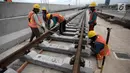 Pekerja mengerjakan pemasangan rel di Depo LRT, Kelapa Gading, Jakarta Utara, Kamis (25/1). Satu rangkaian LRT diperkirakan dapat menampung sekitar 540 penumpang. (Liputan6.com/Arya Manggala)