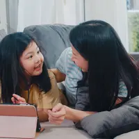 Seorang anak perempuan sedang berdiskusi bersama ibunya sambil menonton tablet (Foto Dok: Freepik/tirachardz).