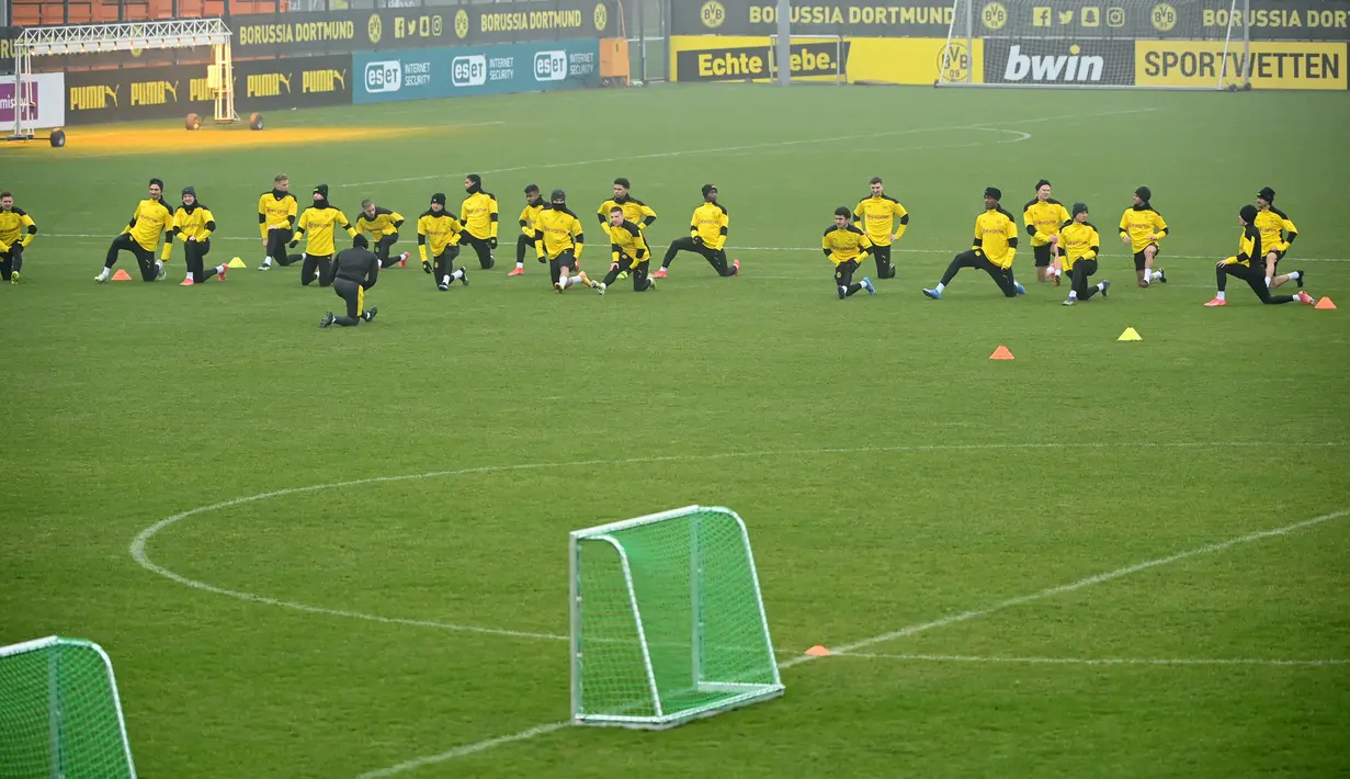 Para pemain Borrusia Dortmund melakukan pemanasan selama sesi latihan di tempat latihan tim di Dortmund, Jerman barat (9/3/2021). Dortmund akan bertanding melawan Sevilla pada leg kedua babak 16 besar Liga Champions di Signal Iduna Park. (AFP/Ina Fassbender)