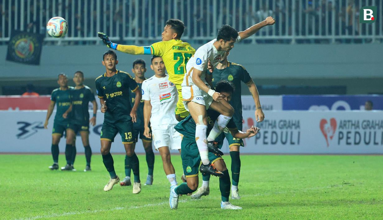Kiper Persikabo 1973, Syahrul Trisna (tengah) berusaha menghalau bola yang mengarah ke pemain Persija Jakarta, Aji Kusuma pada laga pekan kedua BRI Liga 1 2023/2024 di Stadion Pakansari, Cibinong, Bogor, Minggu (9/7/2023). (Bola.com/M Iqbal Ichsan)
